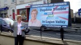 Daphne Trimble posing in front of an election poster mounted on a trailer