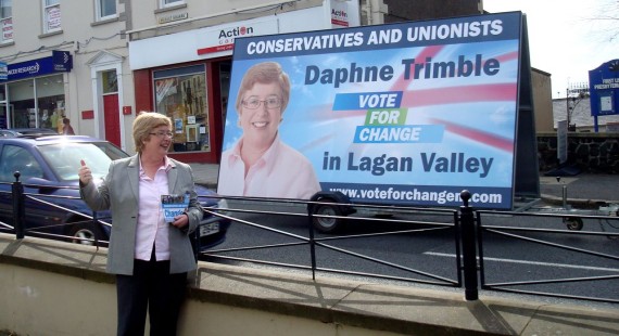 Daphne Trimble posing in front of an election poster mounted on a trailer