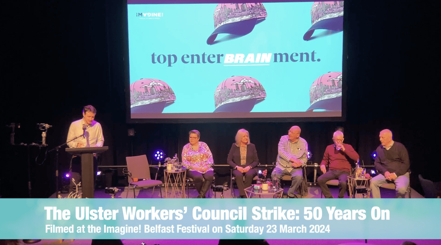 Freeze frame from video of Ulster Workers’ Council Strike: 50 Years On event in Crescent Arts Centre - Connal Parr is standing at the podium - seated near him are Dawn Purvis, Carmel Gates, Harry Donaghy, Jackie Redpath and Jackie McDonald.