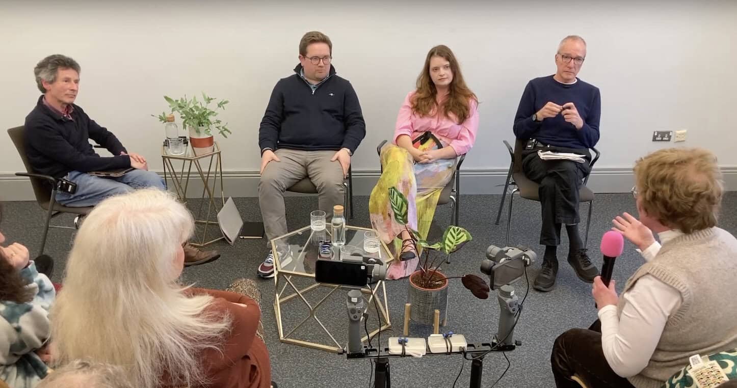 Panel sitting in front of an audience - from left to right, Mark Devenport, Aaron Callan, Emma DeSouza, and Quintin Oliver