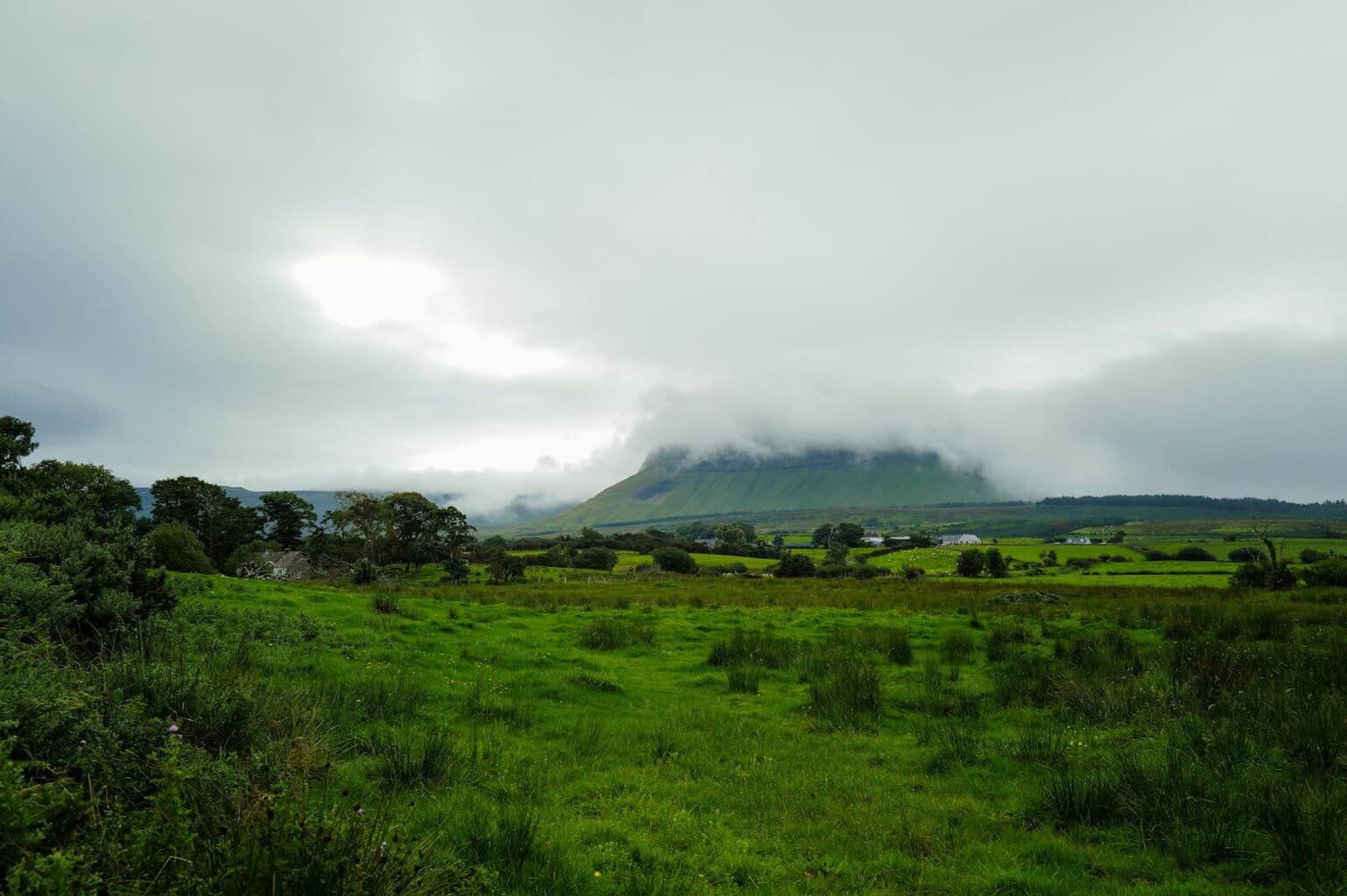 Misty mountain landscape with green fields below