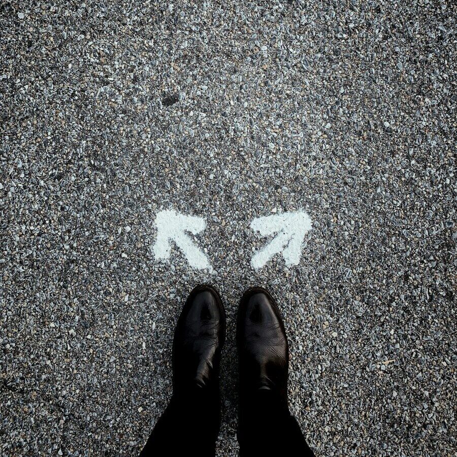 feet on asphalt between two directional arrows